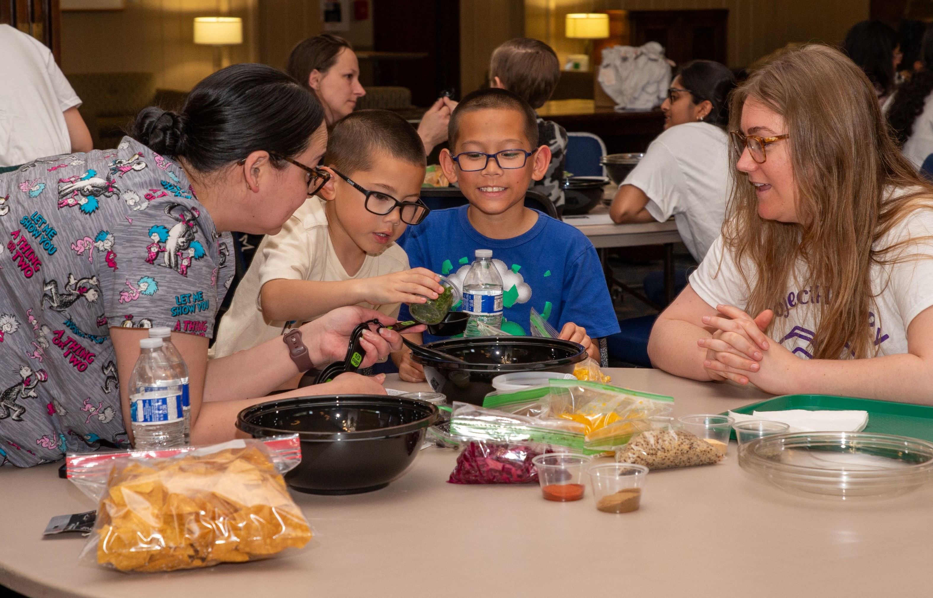 Stacy Tolman-Cordero watches as her children Brayden and Mason make a healthy snack while student doctor Kimberly Glass guides them