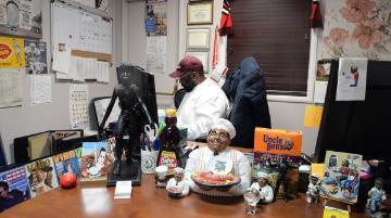 Chef Raymond sitting at his desk, surrounded by his collection of African American items