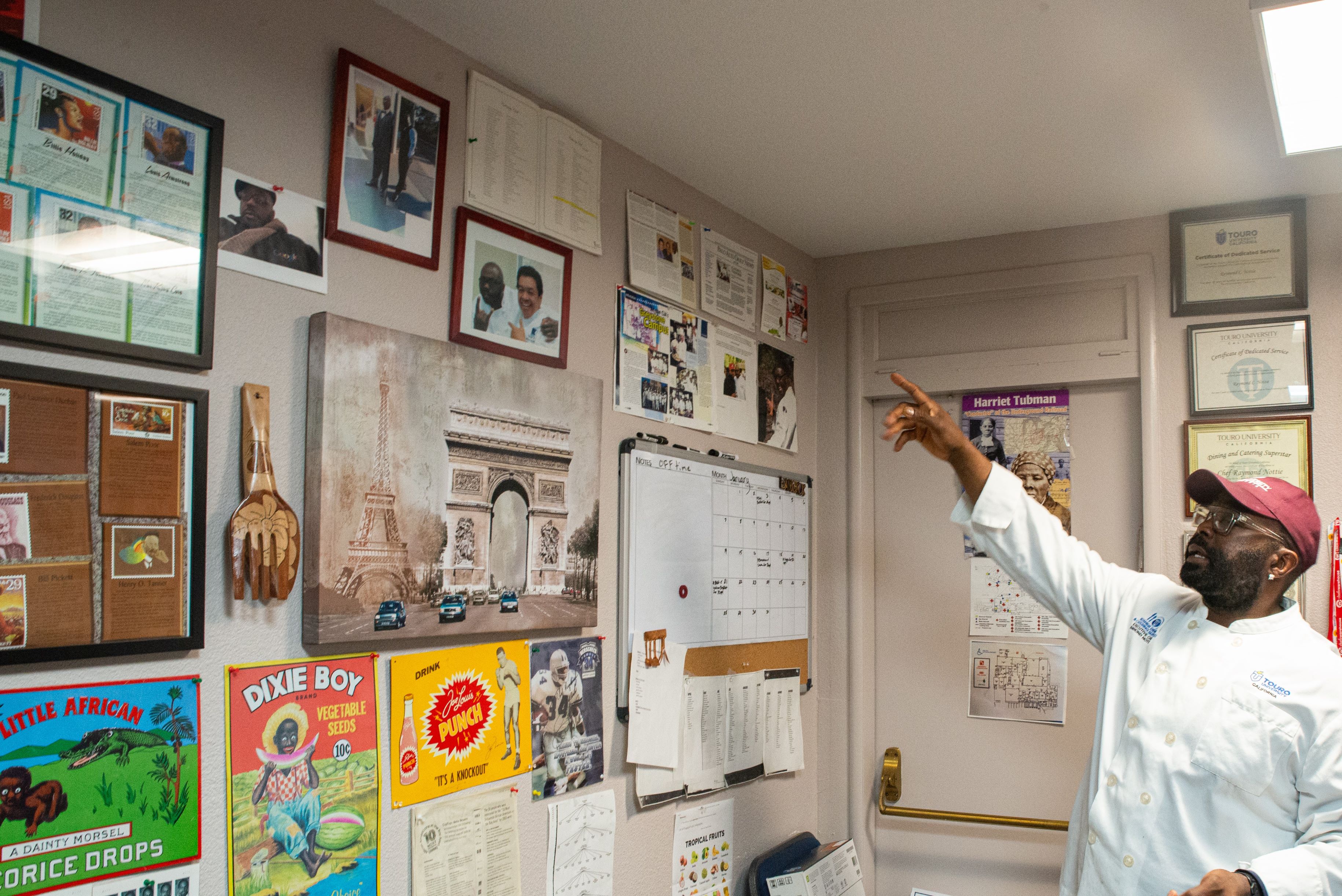 Chef Raymond Nottie points to a wall covered with items from African American history