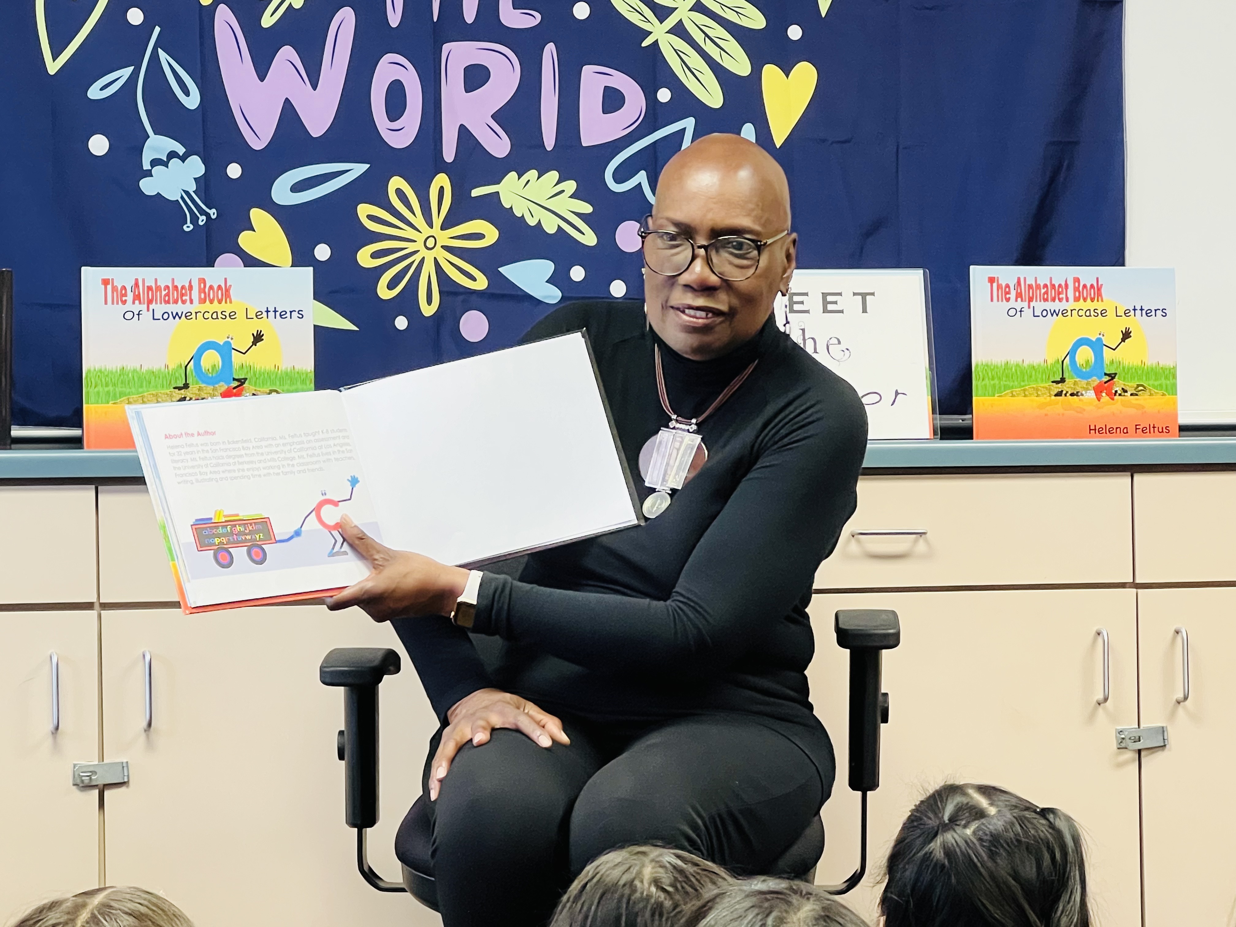 A photo shows Helena Feltus as she reads her book, “The Alphabet Book of Lowercase Letters,” to a group of children in a classroom.