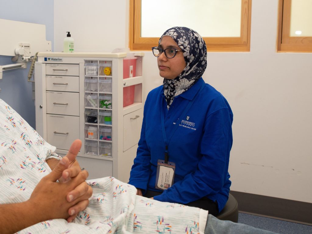 Dr. Sumera Ahmed sits bedside to a patient in a clinical room