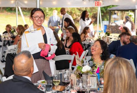 A photo shows Student Doctor Ashley Cao, standing while holding a clipboard and red two-part tickets, as she sells tickets to the prize drawing to guests during the 10th Annual Mosaic Gala, Thursday, Aug. 27, 2026.