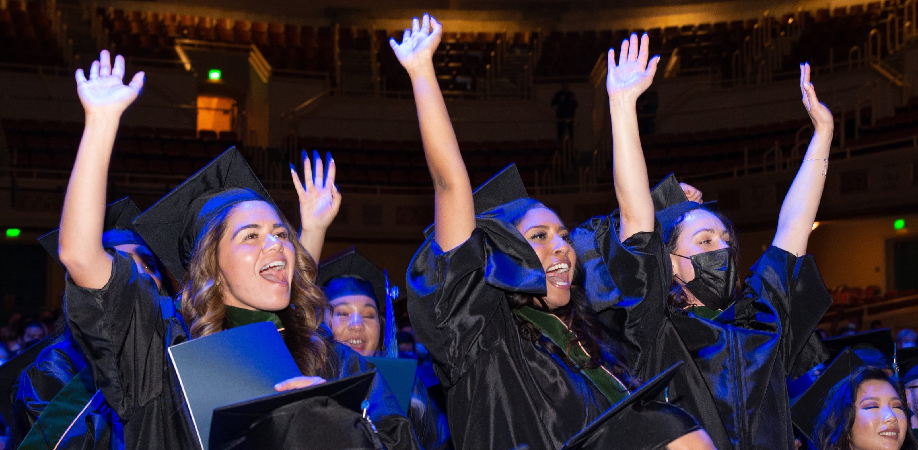 Touro students raise hands in celebration after graduating