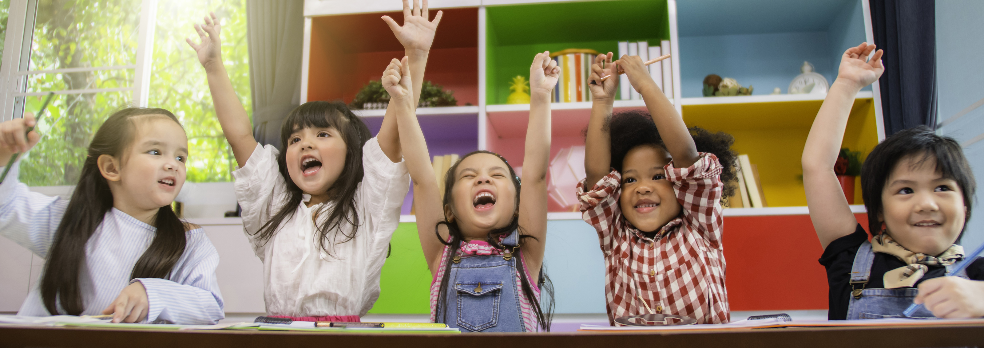 Group of multi-ethnic five little kids children African American, asian and Caucasian happiness together with friend to draw colour pencil to full colour of picture in living room or class room