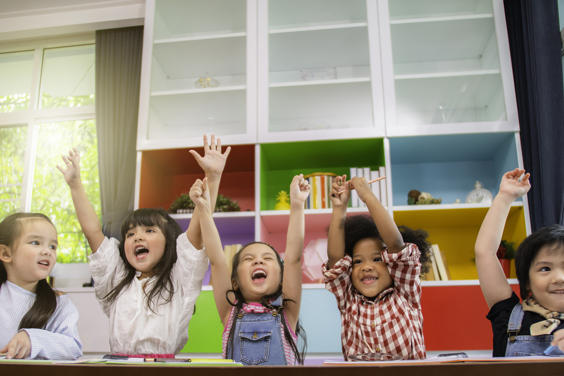 Group of multi-ethnic five little kids children African American, asian and Caucasian happiness together with friend to draw colour pencil to full colour of picture in living room or class room