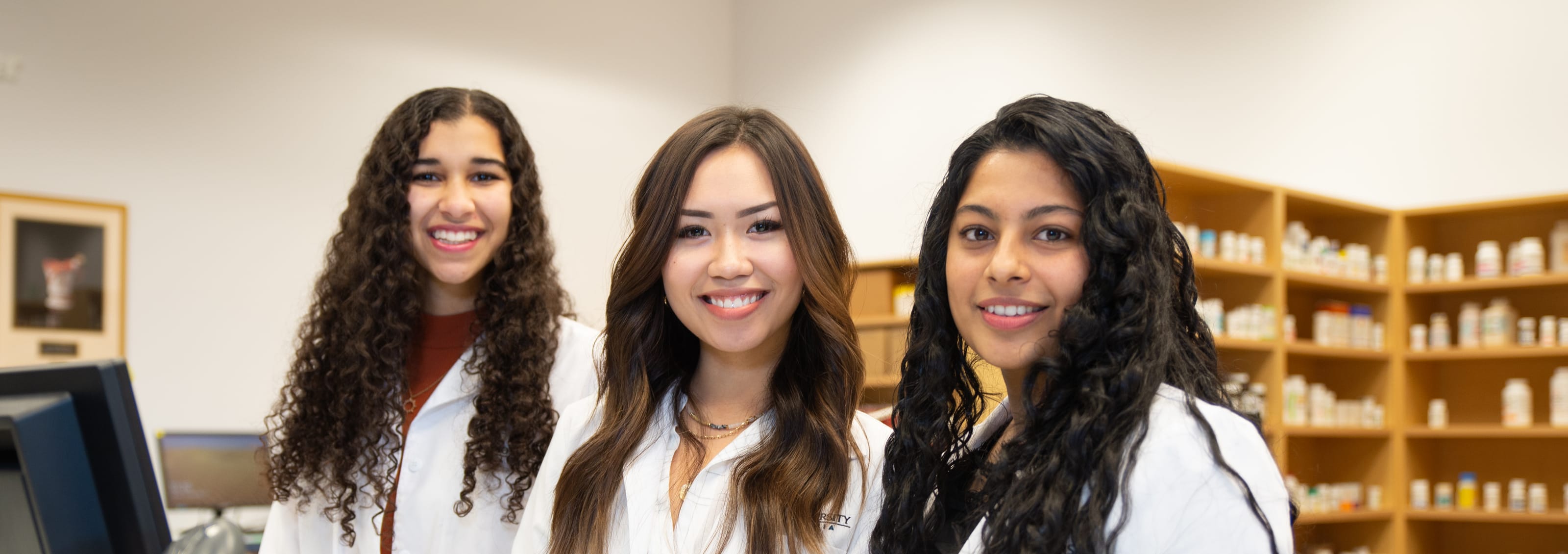 three pharmacy students posing in pharmacy