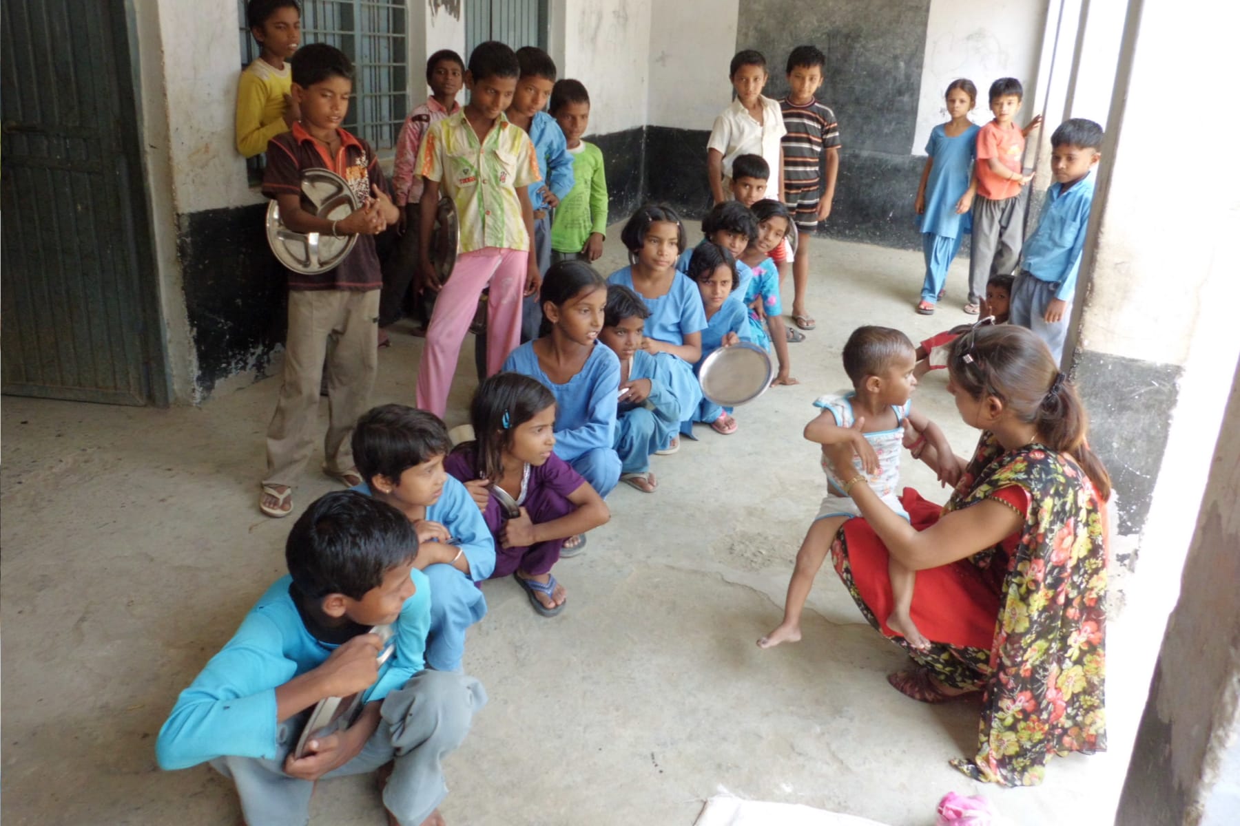 Group of kids outside with one adult holding trays for food.