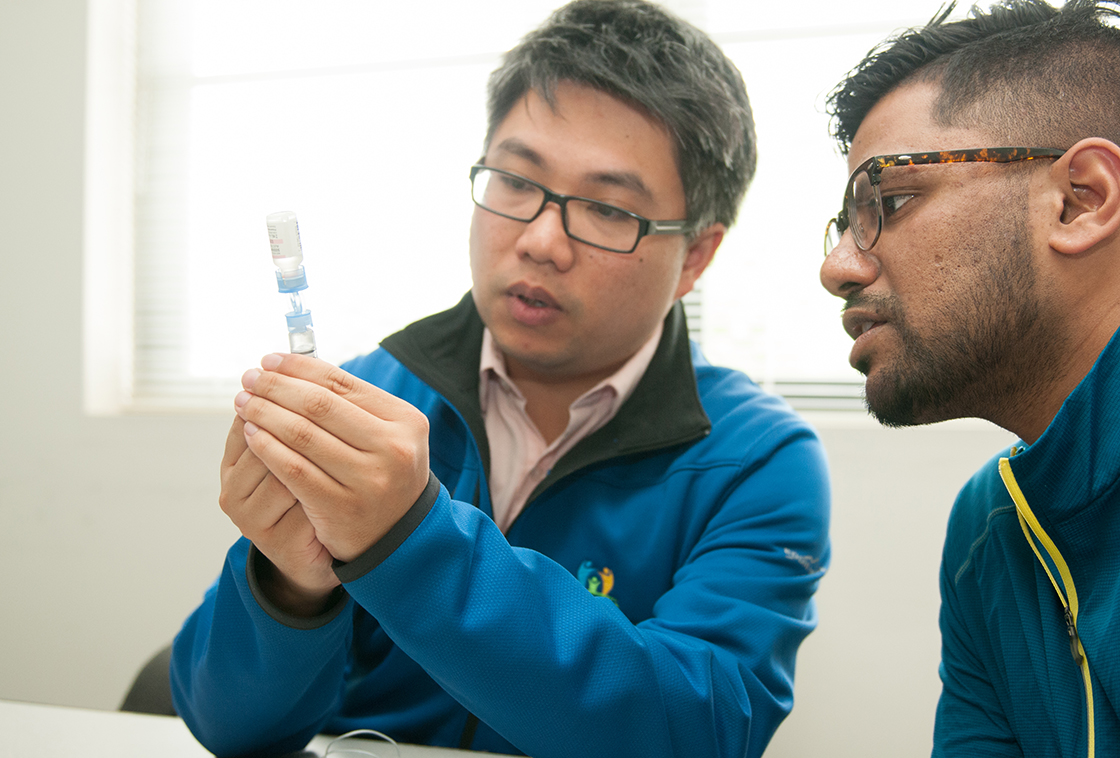 Two male students looking at a medical vial