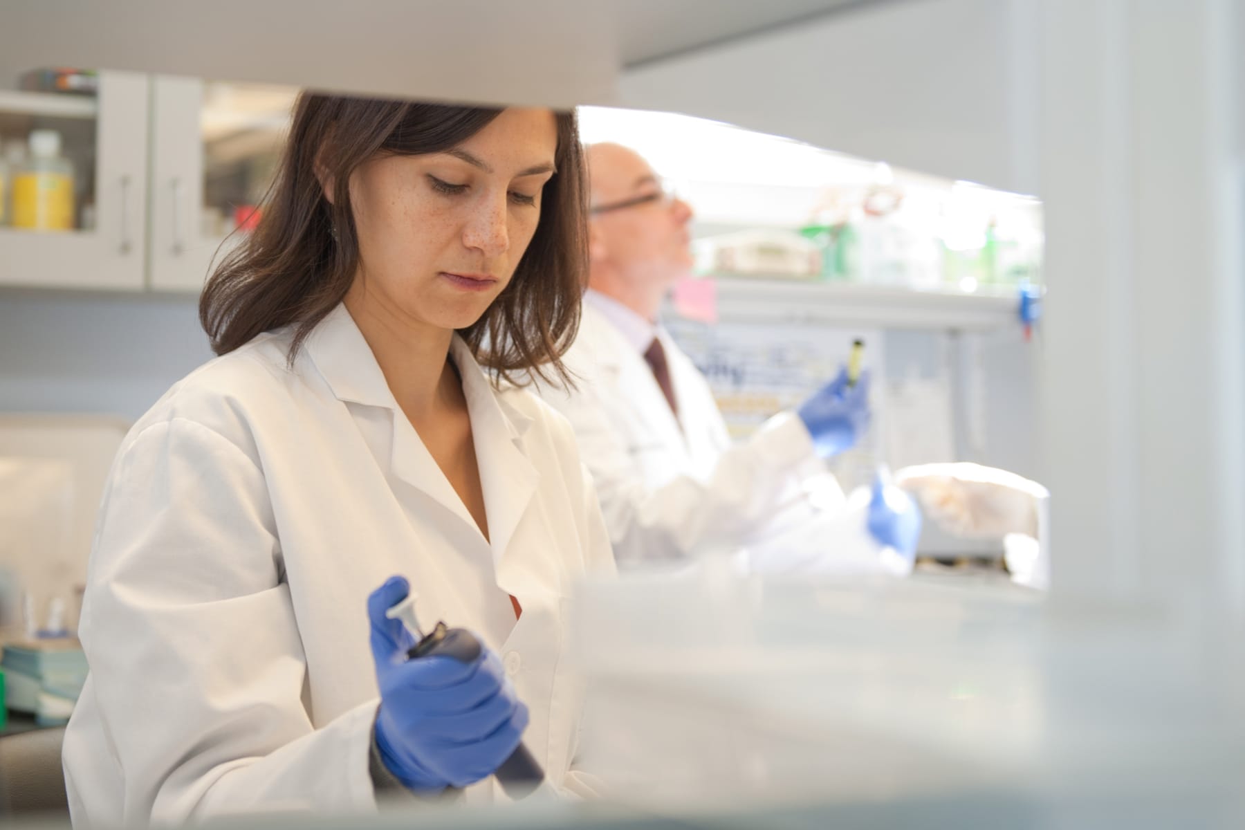 student in white coat working in lab