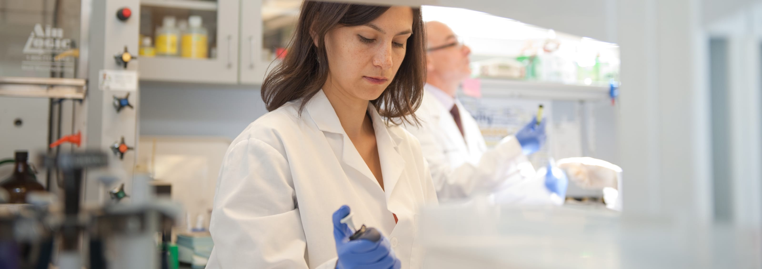 student in white coat working in lab