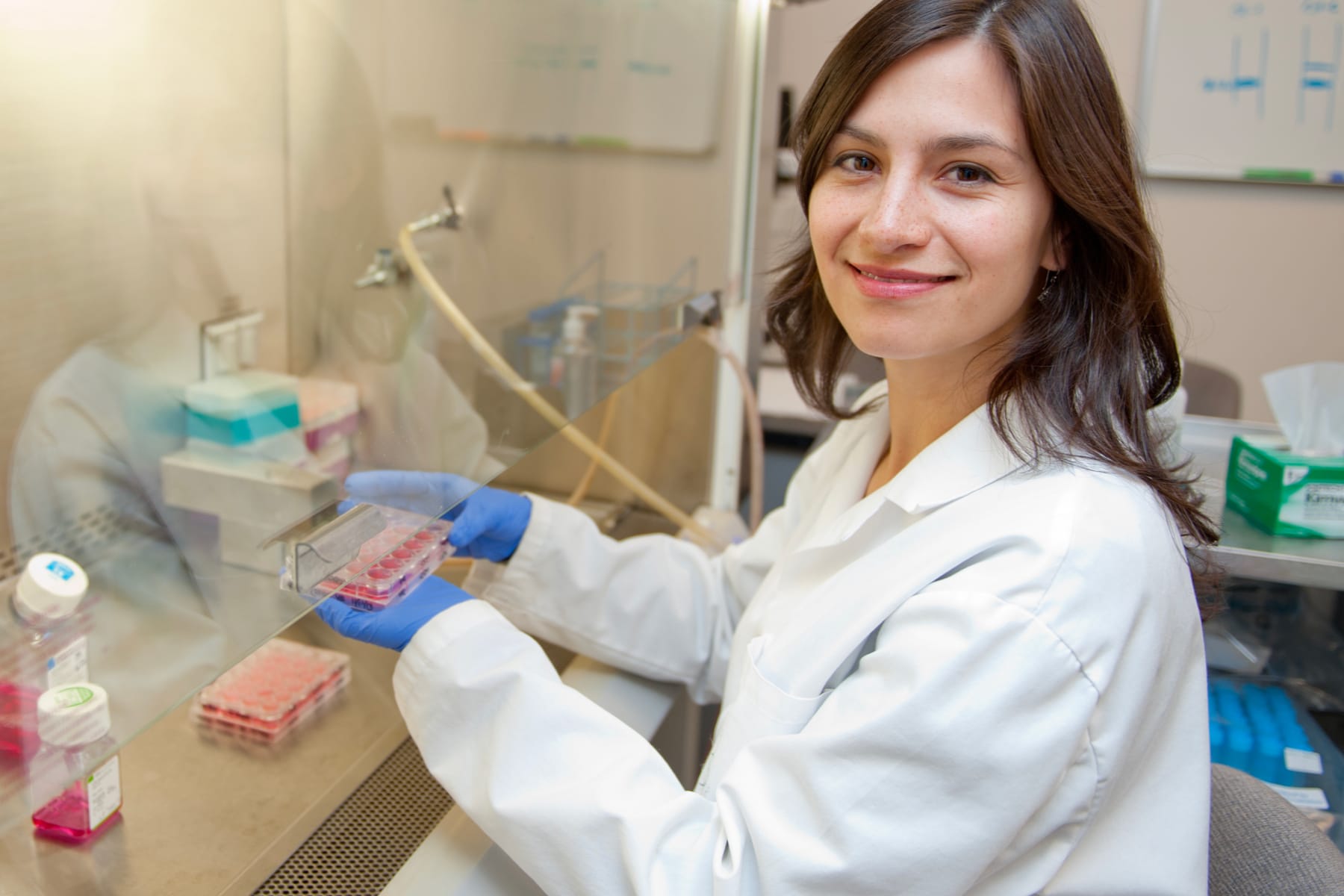 student in white coat working in lab