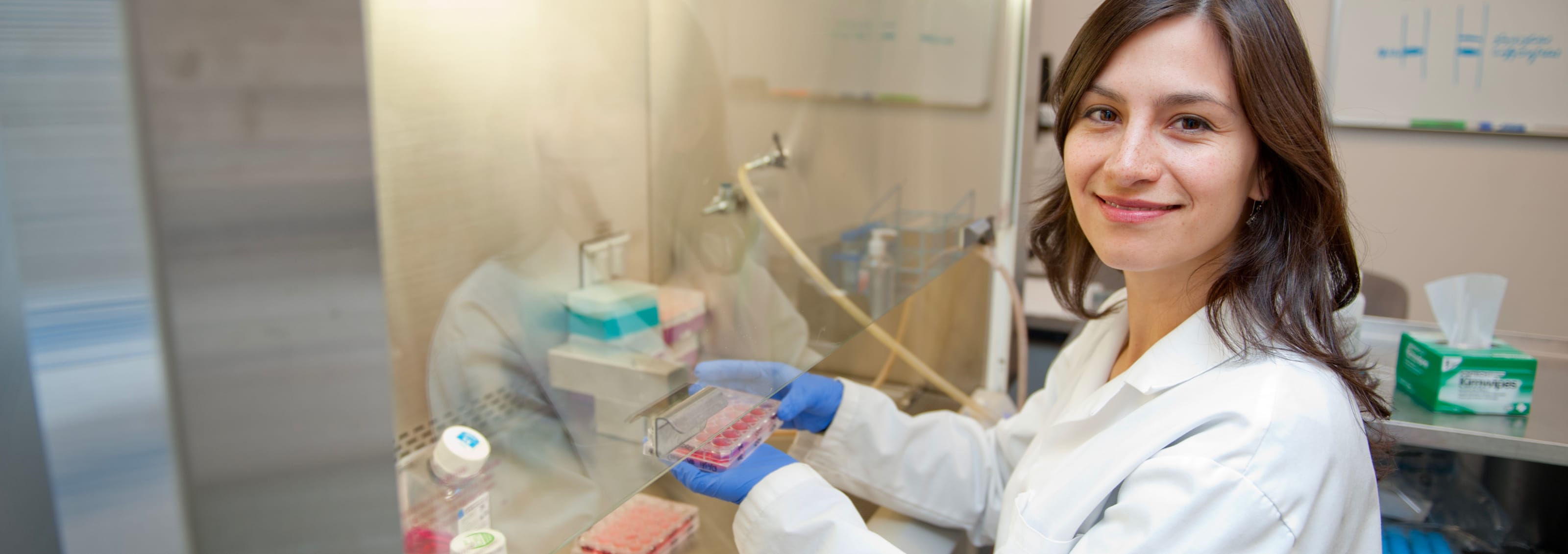 student in white coat working in lab