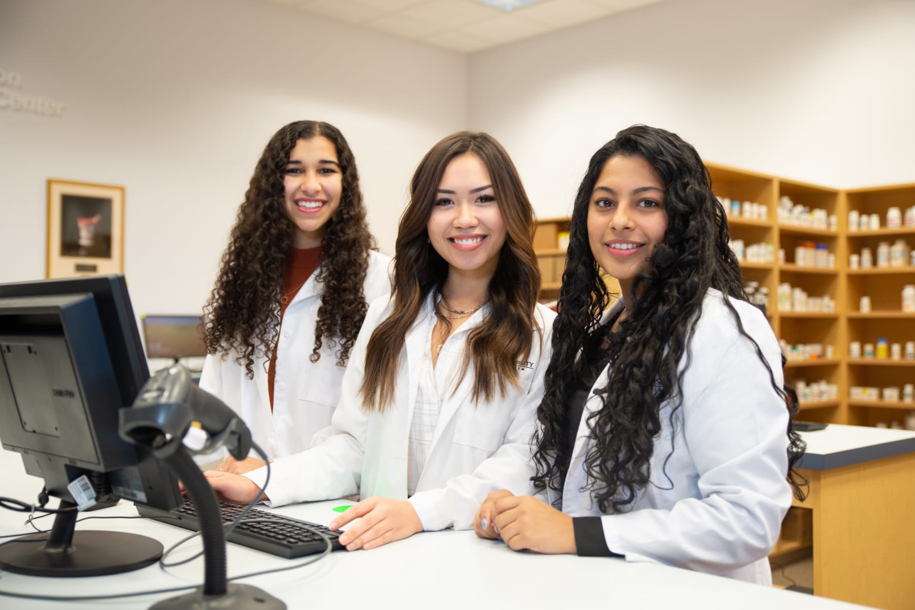 three pharmacy students posing in pharmacy