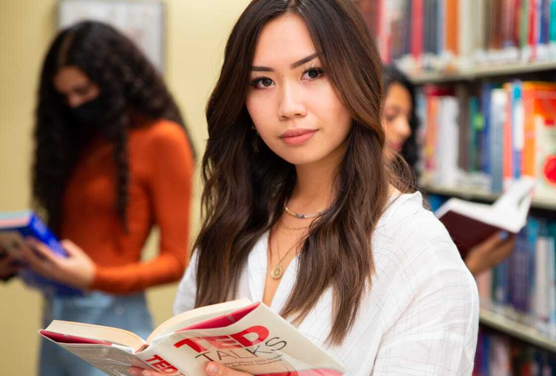 Female student standing and reading in library