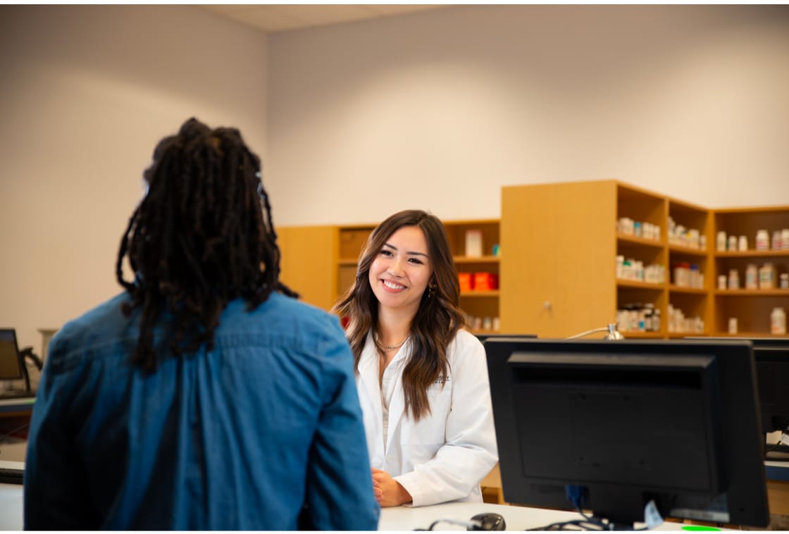 Student pharmacist smiling and helping customer