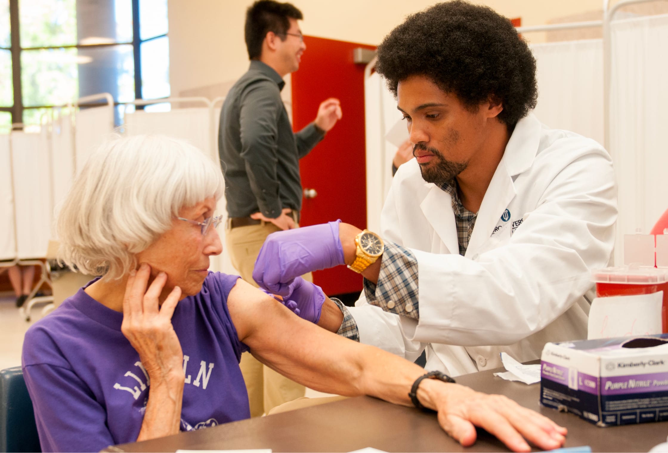 TUC pharmacy student administering a vaccine to a senior woman