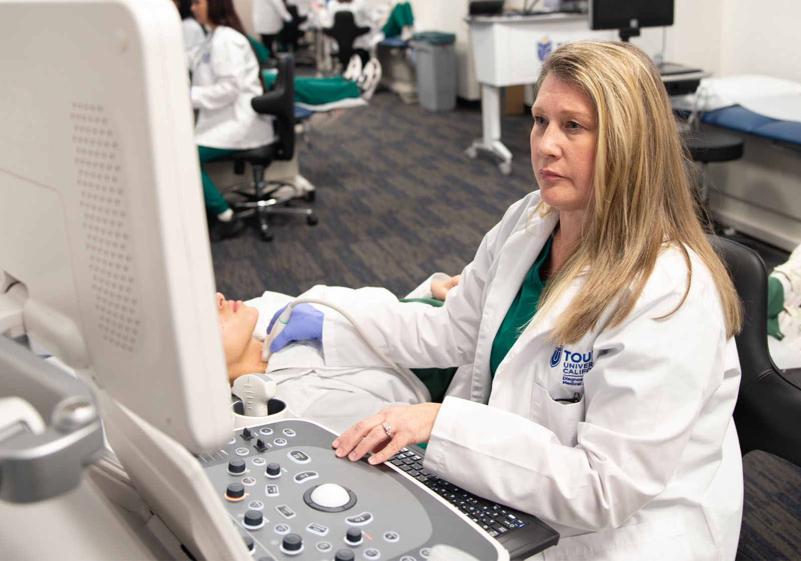 A Touro California Sonography student analyzes her monitor results of the sonogram she is giving to a patient.