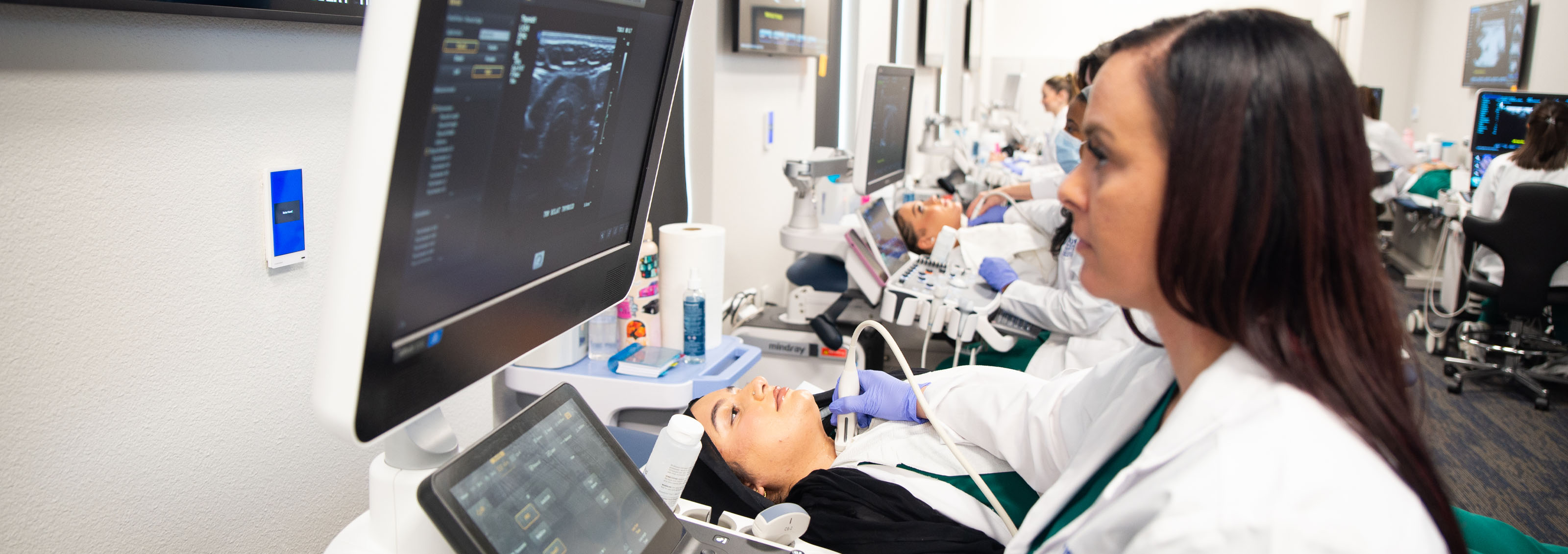 A Touro California Sonography student analyzes her monitor results of the sonogram she is giving to a patient.