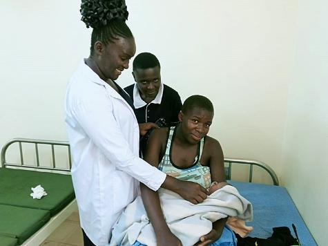 A healthcare worker checks a newborn baby and mother.