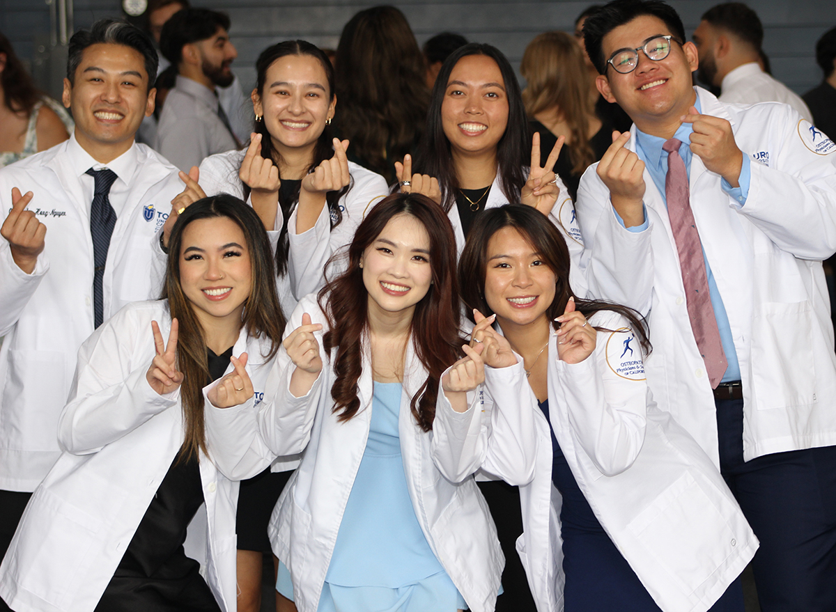 Group of seven Class of 2028 students pose in white coats at the White Coat Ceremony.