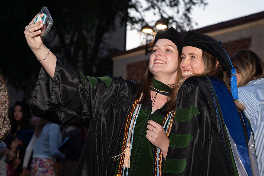 A photo shows a pair of Touro University California students with the Class of 2024 as they take a selfie after commencement ceremonies outside the Sacramento Memorial Auditorium in May.