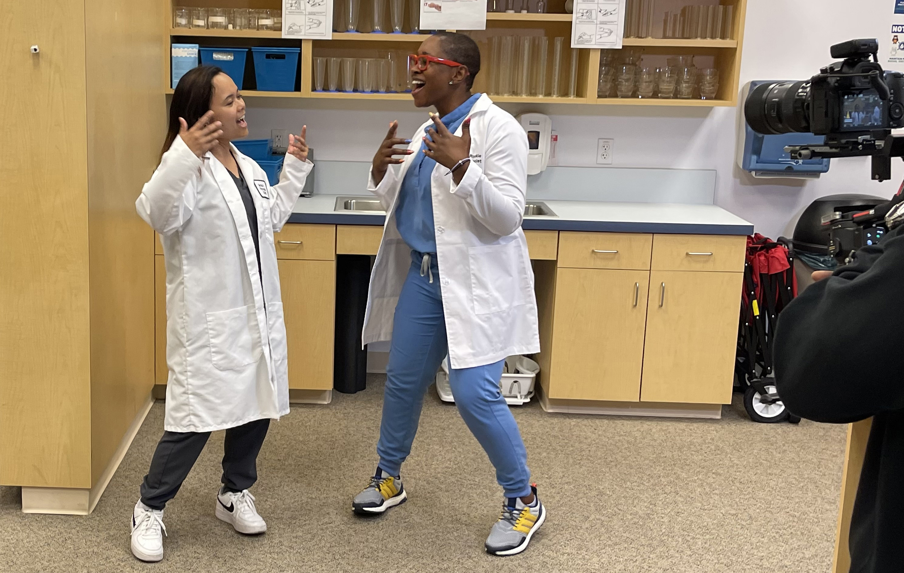 A photo shows Touro University California Alumnae Drs. Bernice (Wright) Perez, left, and Brigitte Ouabo as they sing and dance while recording a segment for a music video parody inside the Pharmacy Practice Center on campus, Aug. 12, 2024.