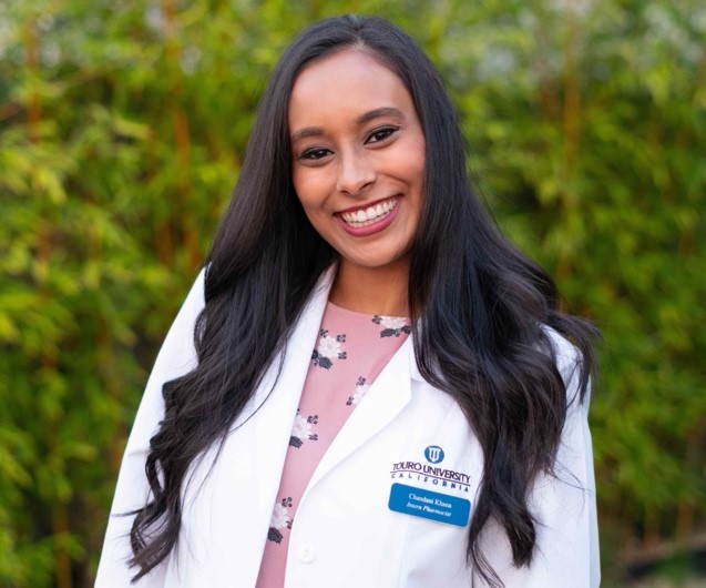 PharmD student, Chandani Khana, in white coat smiling and posing outdoors.