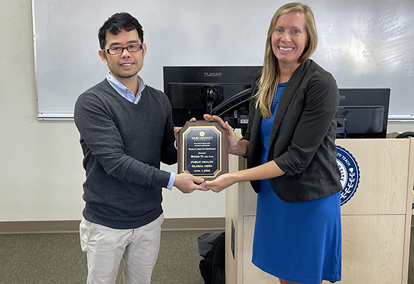A photo shows Dr. Siyan Yi, left, holds a Global Health Public Hero Award presented to him by Dr. Carinne Brody, Associate Professor of Public Health and Associate Program Director of Public Health’s Global Health Concentration, right, after a lecture by Yi to Touro University California MPH students in a classroom at the Farragut Inn on campus, Wednesday, Oct. 11, 2023.