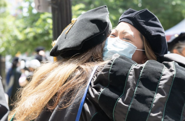Newly graduated students hug one another