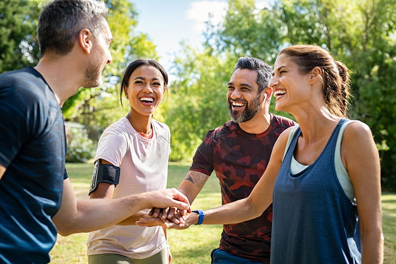 An image from Ridofranz / iStock shows four people smiling as they come together to exercise. The benefits of physical activity extend beyond keeping your weight in check.