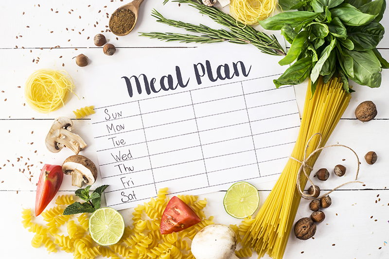 An image from iStock illustrates a printed but blank weekly meal plan list surrounded by samples of fresh pastas, fruits, nuts and vegetables. The benefits of a healthy diet are there for the taking.