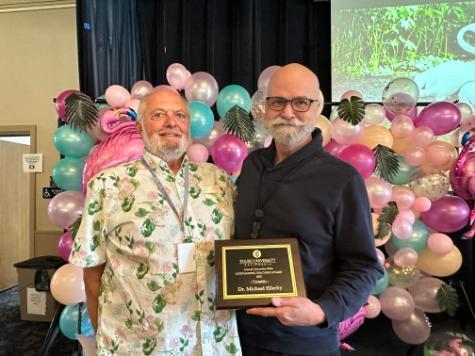 Former Dean Jim O\'Connor standing next to Professor Micheal Ellerby who is holding an award that reads Teacher of the Year 2023