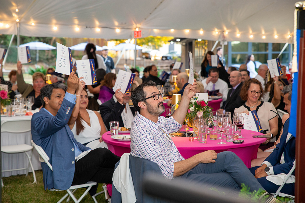 Mosaic Gala attendees raise their bidding booklets to start the evening of live auctions benefiting the Mosaic Scholarship. 