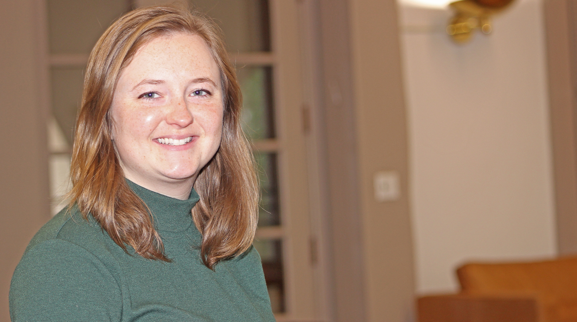 A photo shows Alumni Association Scholarship recipient Natalie Brown smiling while in the Great Room at Wilderman Hall.