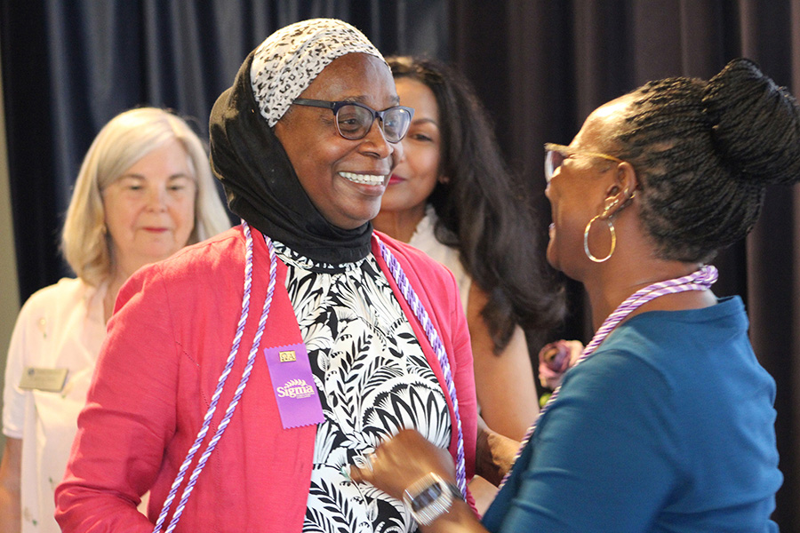 A photo shows School of Nursing master\'s degree candidate Sherry Blackburn, center, who smiles as she is congratulated by Alumna Nikitia "Niki" Hardwick, right, during the Sigma Honors induction ceremony on the Touro University California campus, Thursday, Sept. 5, 2024. SON Assistant Professor and Graduate School of Education Alumna Kathleen Hahn, left, and two-time SON Alumna Dr. Rasika Cunningham look on after having greeted Blackburn.