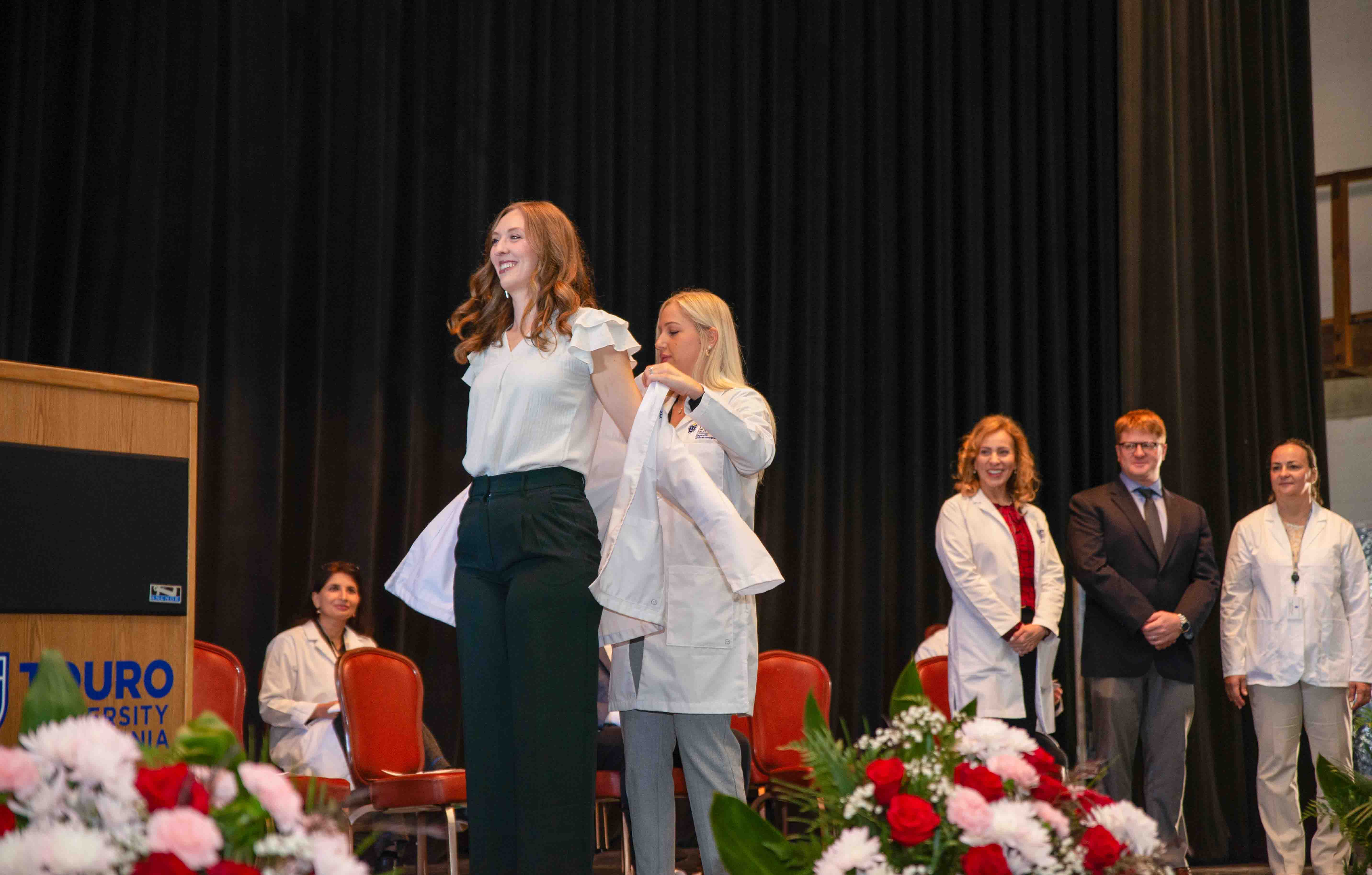Sonography faculty shake hands with students as they receive their white coats.